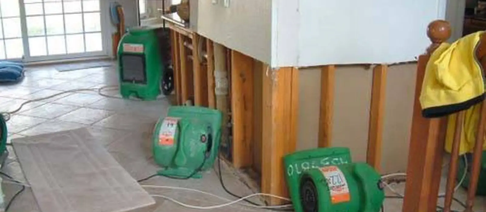 Drying fans set up beside walls cut open down to the studs