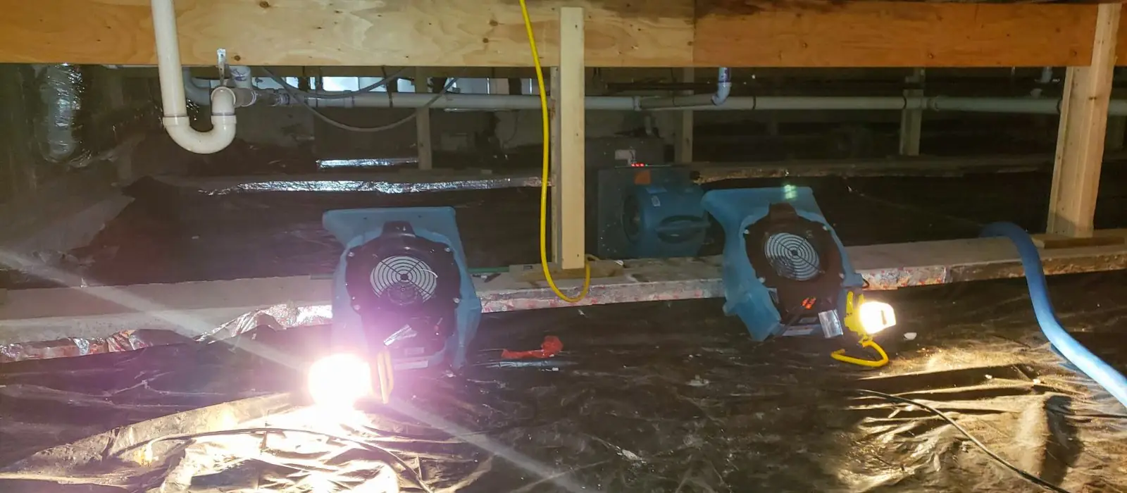Crawl space with drying fans, plastic sheeting and exposed framing